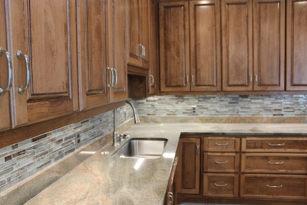 Home kitchen with wood cabinetry and stone countertops at The Orchard at Stone Creek, Hahira GA